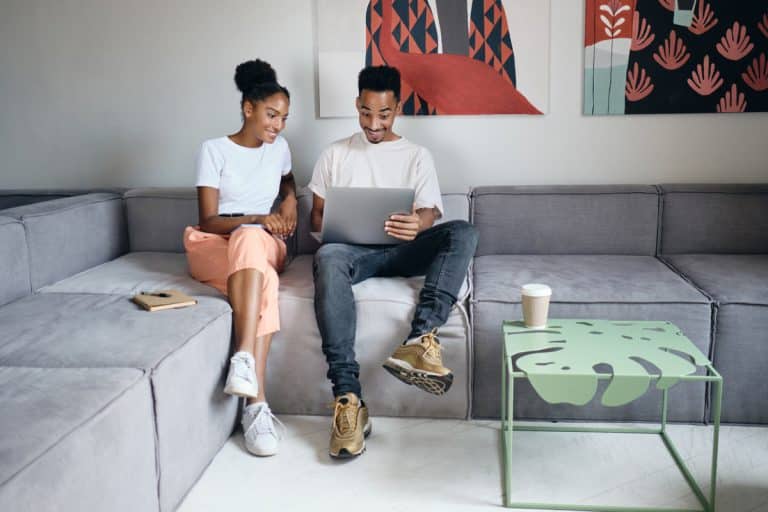 young attractive casual african american couple joyfully working laptop together sofa modern home Loans Online